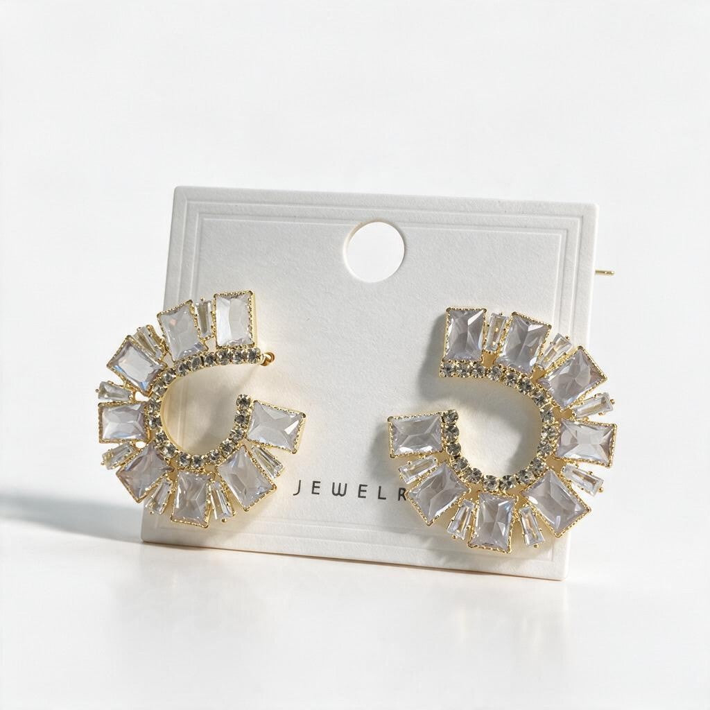 Pair of gold emerald cut crystal crescent earrings on a white display card