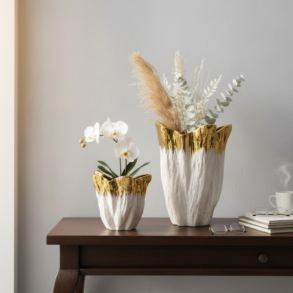 Two sizes of the gold dipped vase on a dark console, one orchid and one with pampas