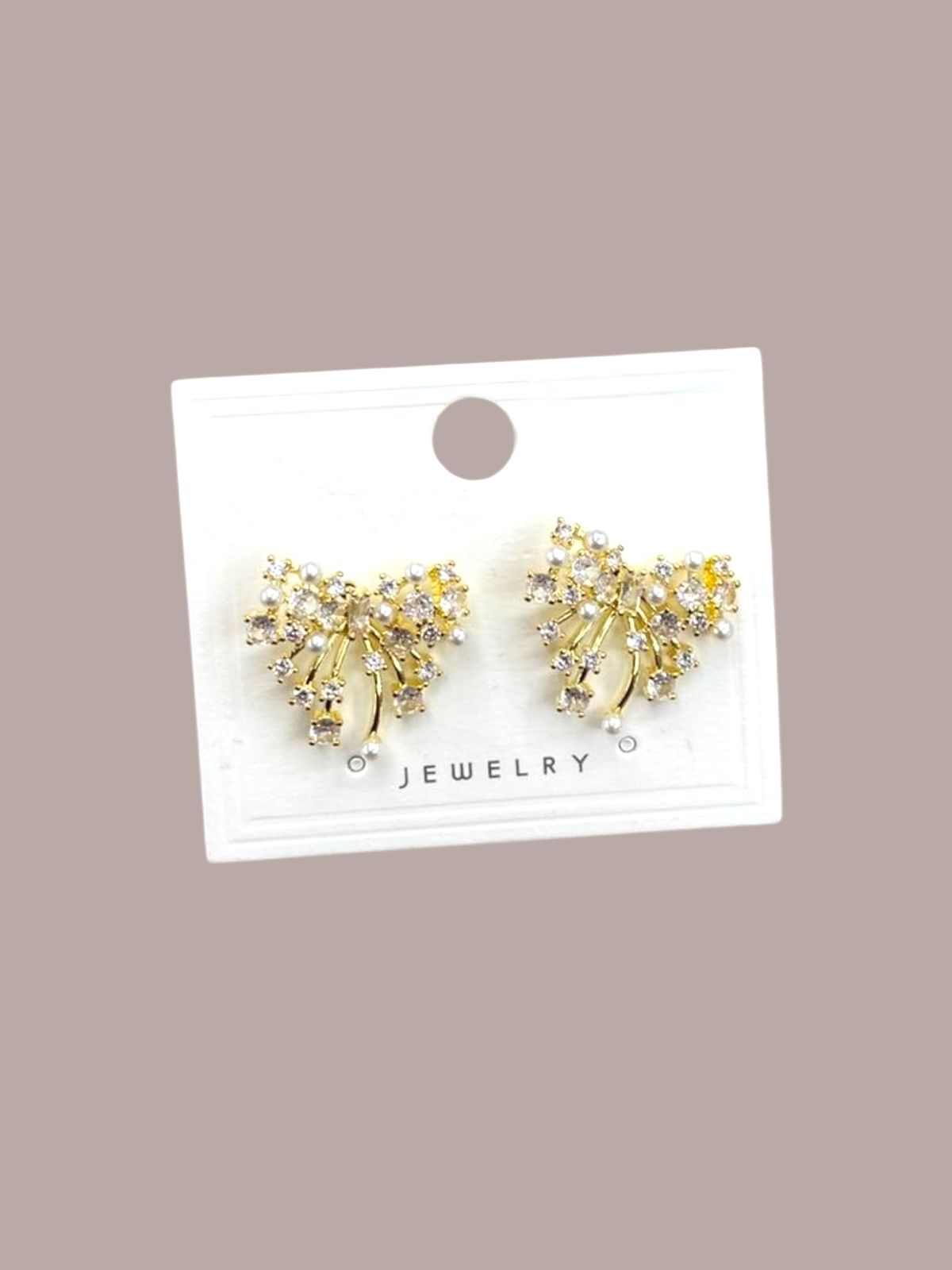 Gold sparkly bow earrings on a jewelry card against a beige background