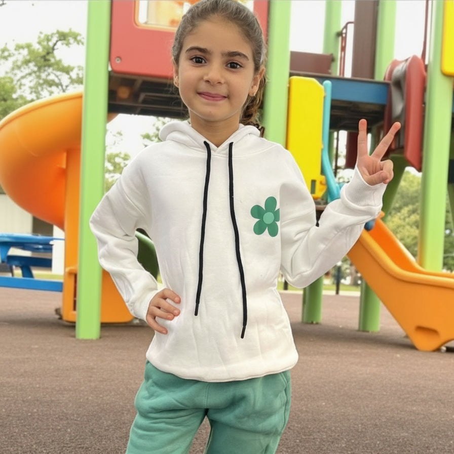 White hoodie with a green daisy on the chest worn with green joggers at a playground
