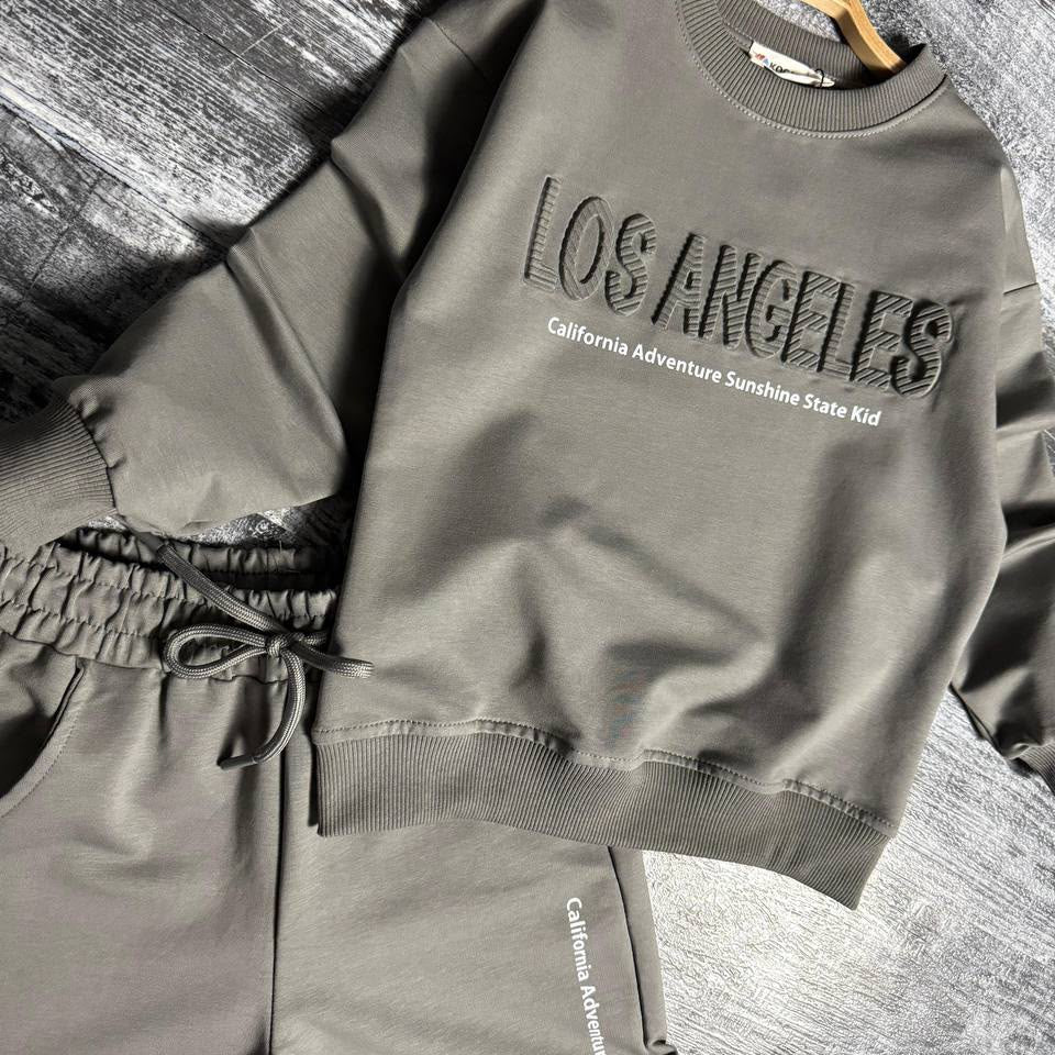 Grey Los Angeles sweatshirt and joggers laid flat showing the raised lettering