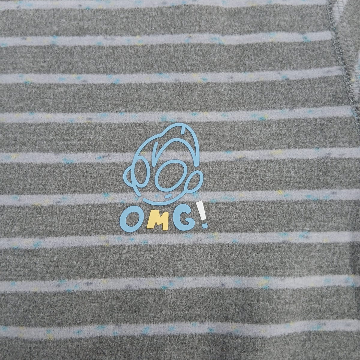 Close up of the blue outlined chest motif with OMG lettering on grey stripe pyjama fabric