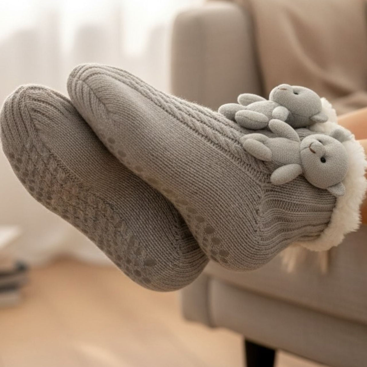 Grey socks with teddy designs worn by a person sitting on a couch.