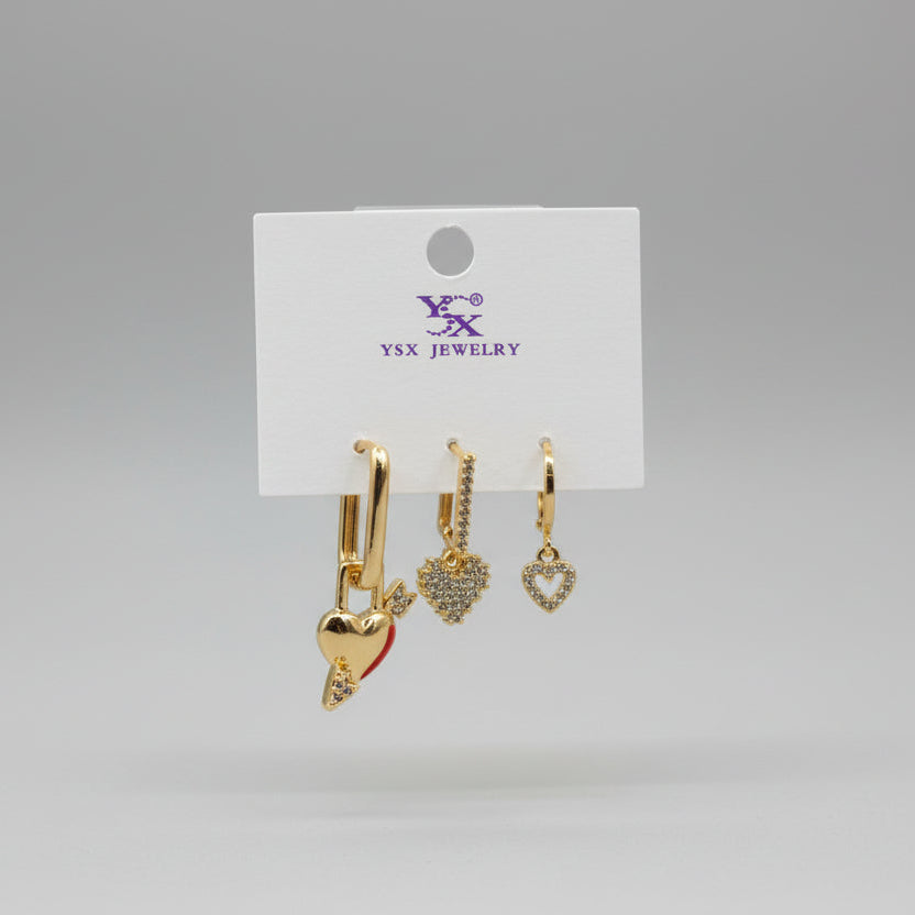 Gold heart-shaped earrings on a Jewelry card against a grey background