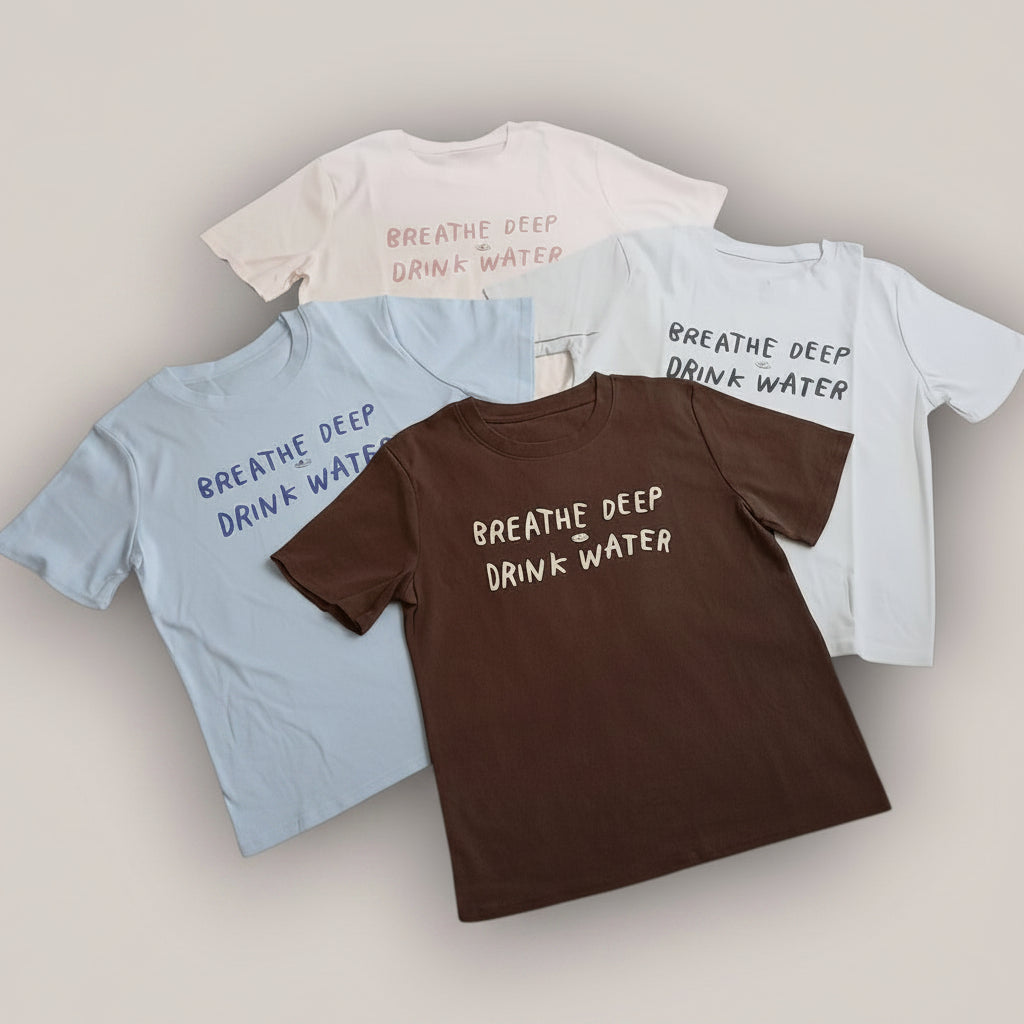 Four t-shirts with 'Breathe Deep Drink Water' text on a light gray background