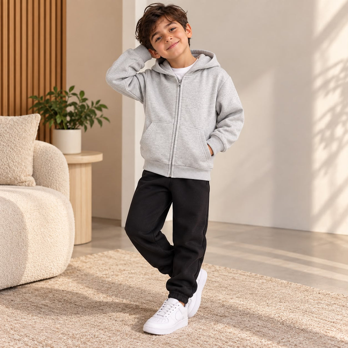 Boy smiling in a grey marl zip hoodie and black cuffed joggers, hand behind his head