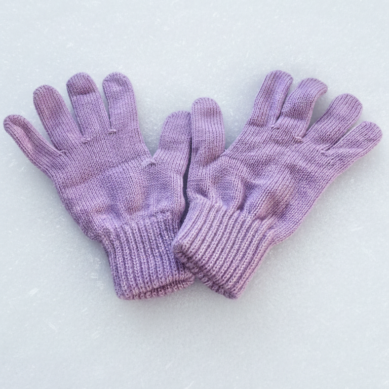 Lilac knitted kids gloves on snow