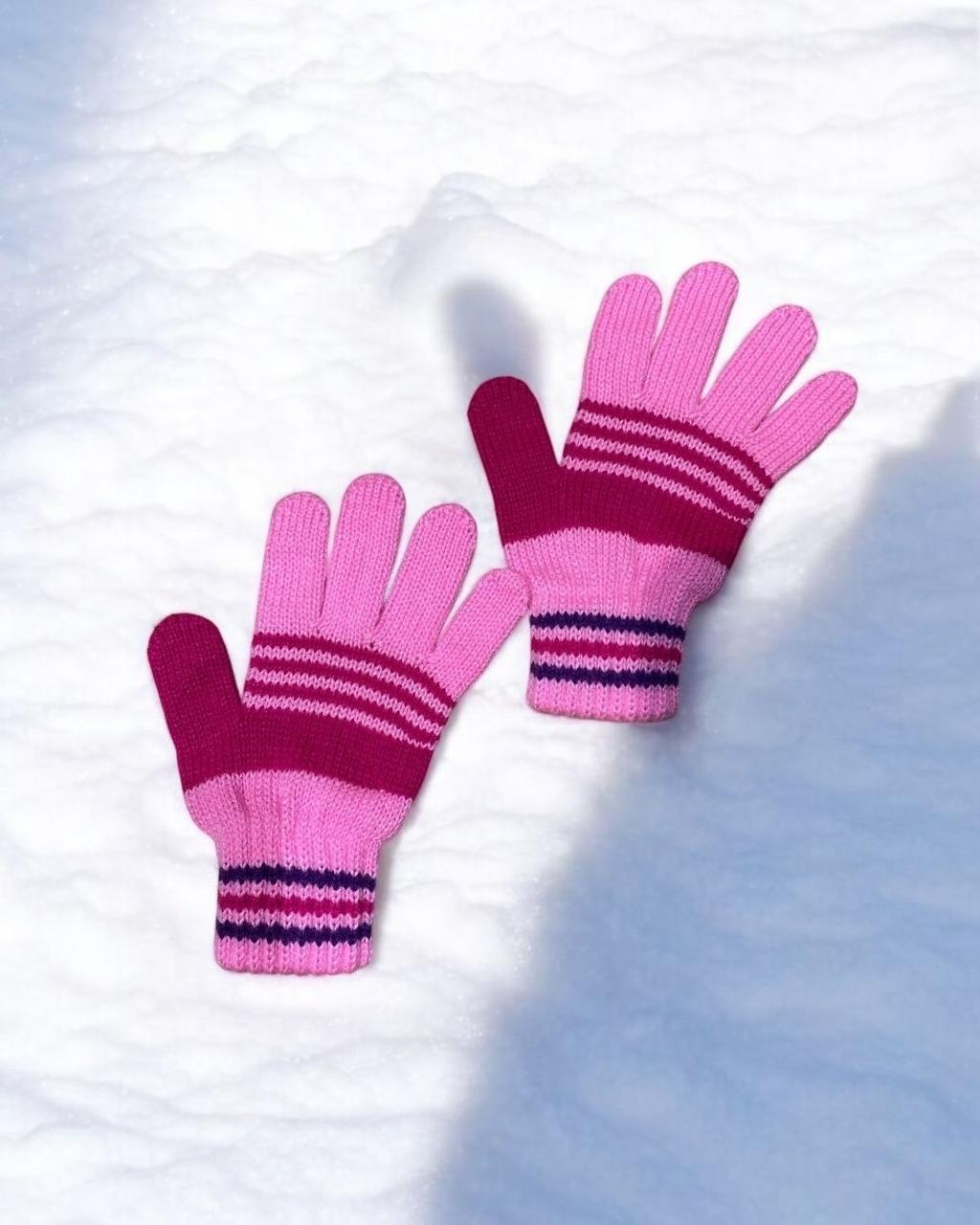 Two tone pink knitted gloves with magenta stripes on snow