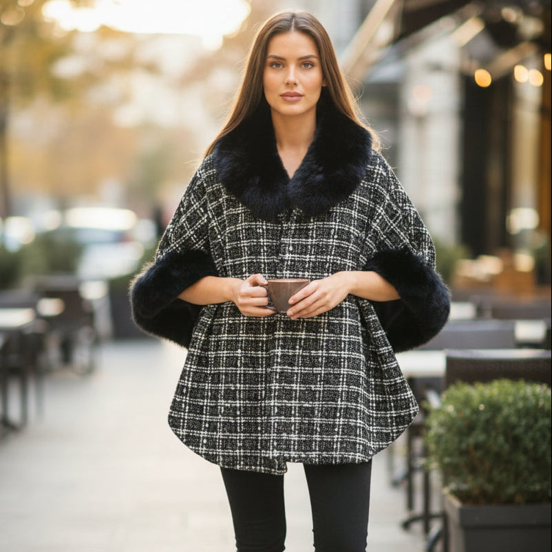 Woman wearing a black and white checkered puncho with a fur collar on a city street