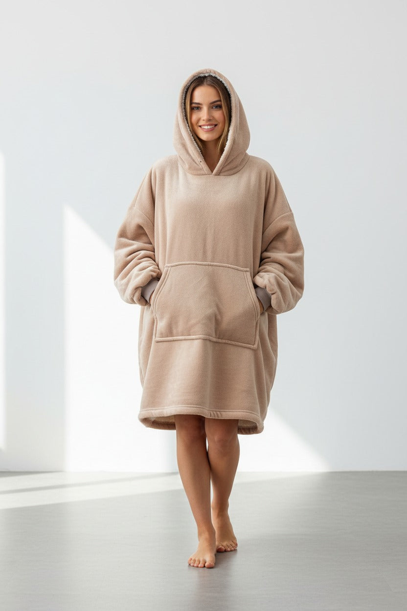 Person wearing a beige hooded garment in a minimalistic setting