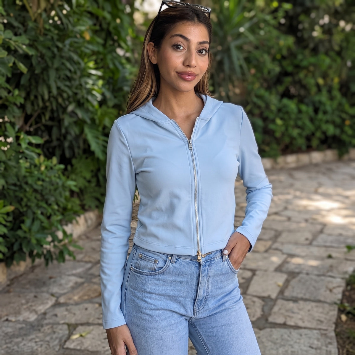 Pale sky blue slim zip hoodie in smooth stretch fabric, cropped at the waist of blue jeans