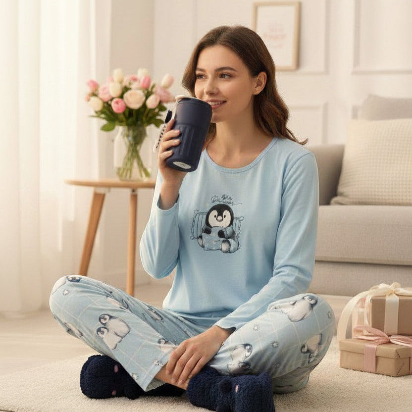 Woman in a light blue penguin print pyjama set relaxing on a couch with a mug - Jack Gifts Online Lebanon