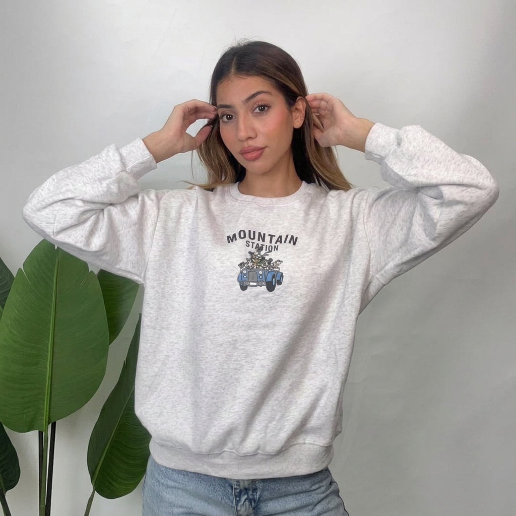 Light grey Mountain Station sweatshirt worn with hands raised, showing ribbed cuffs and hem