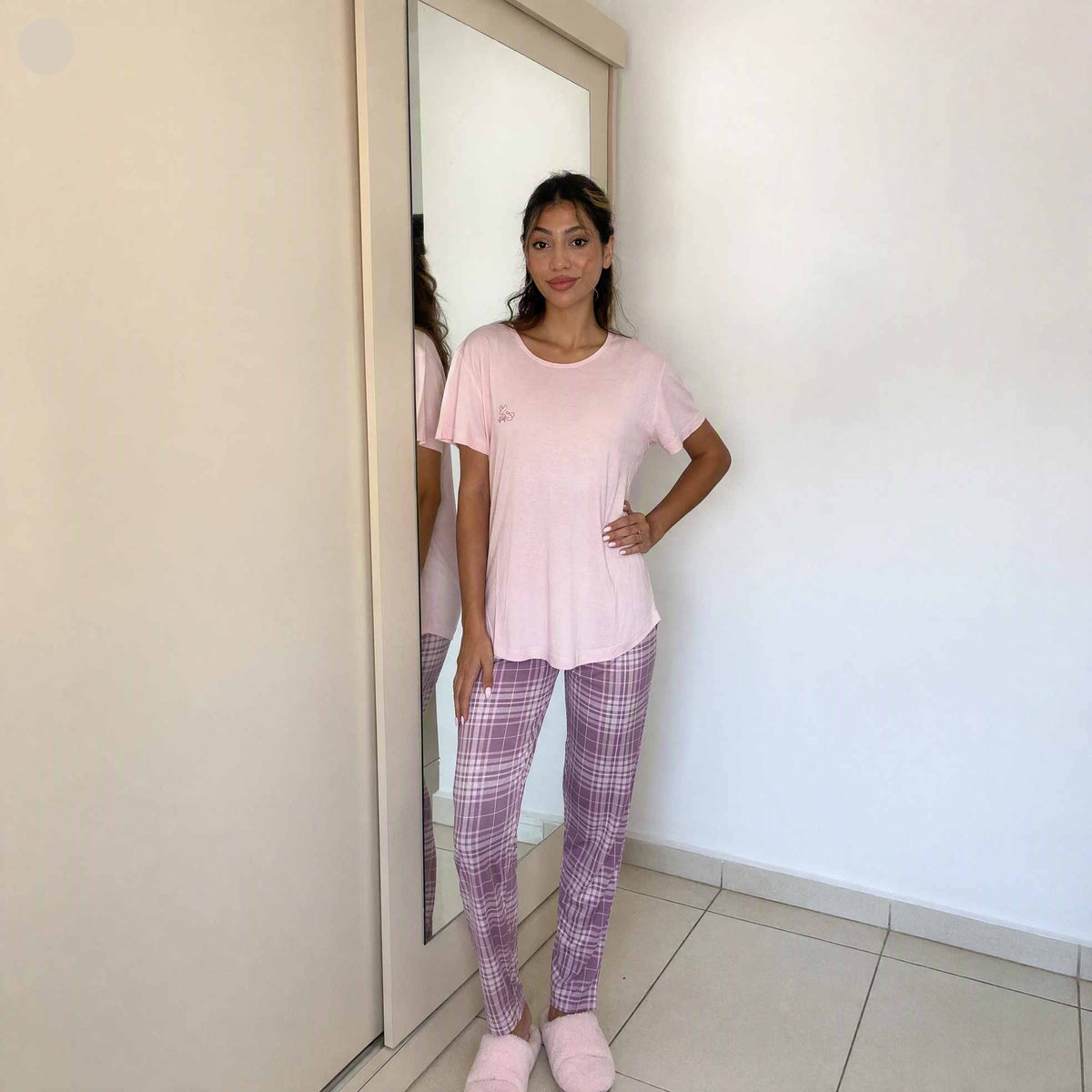 Women's pale pink pyjama top with lilac check bottoms and fluffy slippers