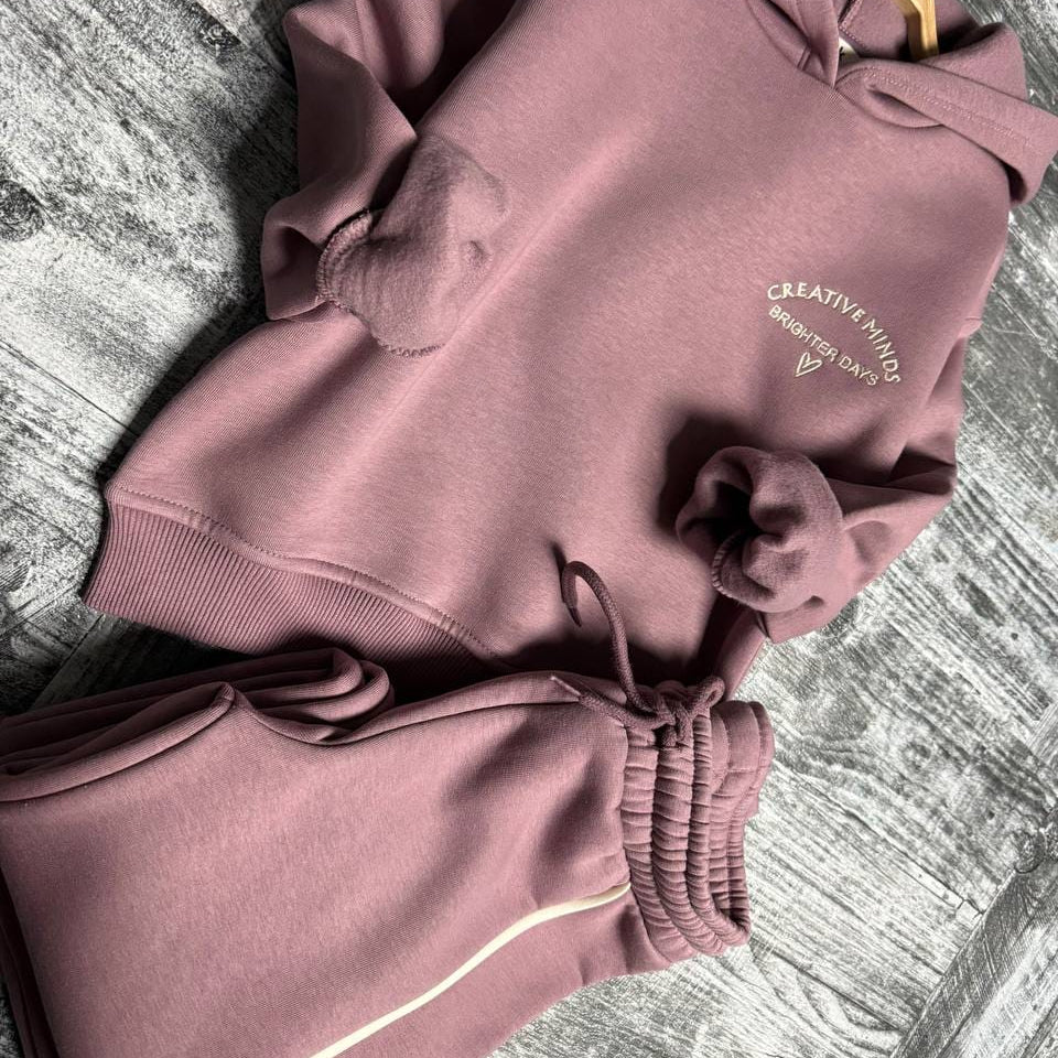 Mauve hoodie and wide leg drawstring pants laid flat on a wooden floor