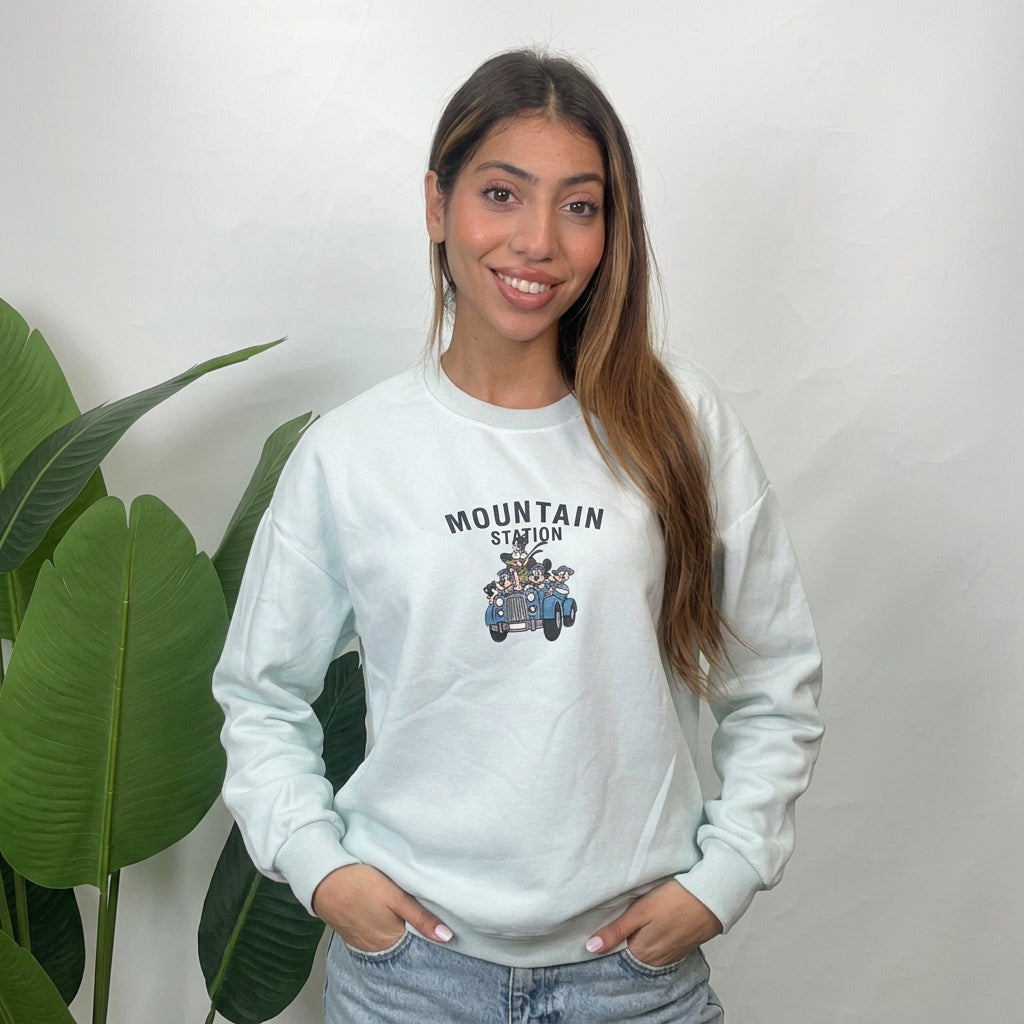 Woman wearing a mint crew neck sweatshirt with Mountain Station lettering and a vintage car print