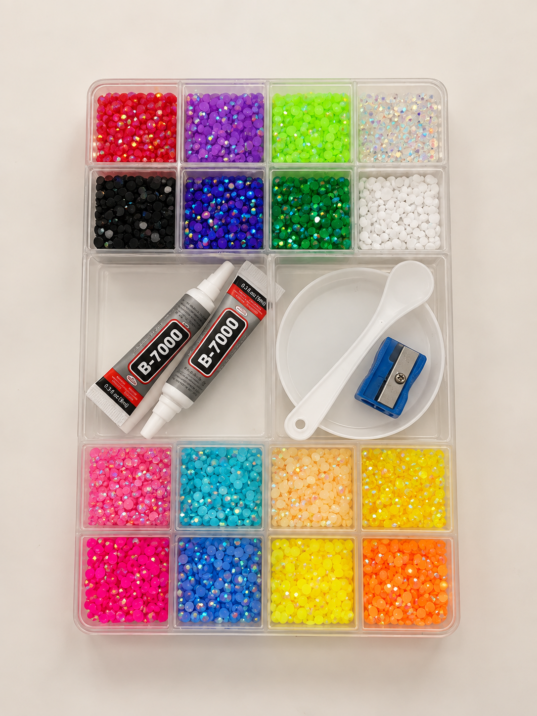 Clear storage box of multicolour flat back rhinestones with craft glue, tray and scoop