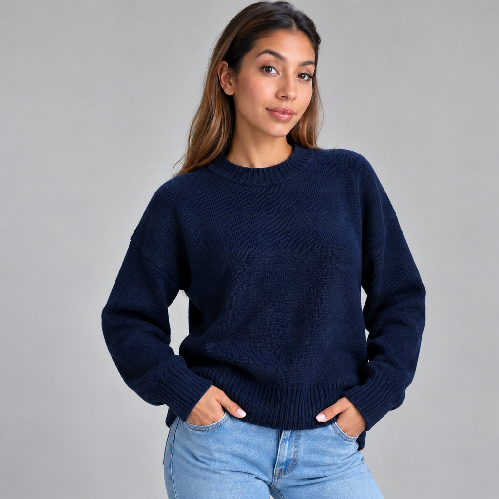 Woman in a navy blue chunky wool knit sweater and light jeans standing with both hands in her pockets