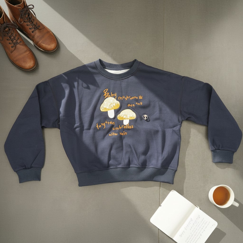 Close view of golden mushroom embroidery and amber script on navy fleece