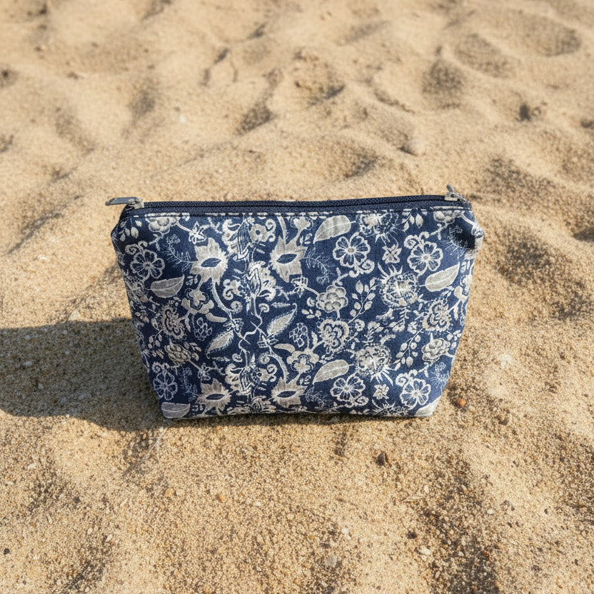 Blue floral-patterned pouch on sandy ground