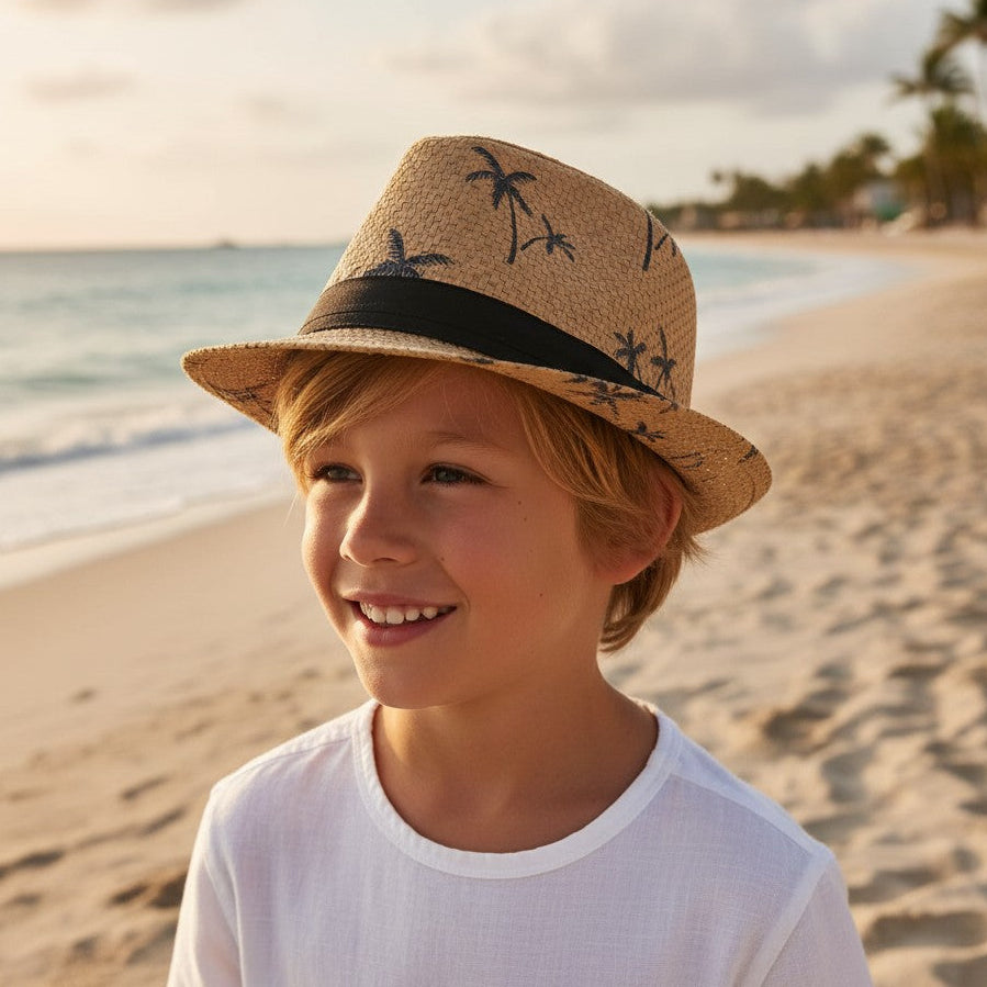 Smiling boy in a tan straw fedora sun hat with a palm tree print and black ribbon band