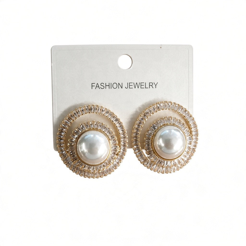 Gold pearl stud earrings circled by spiralling clear crystals on a white card