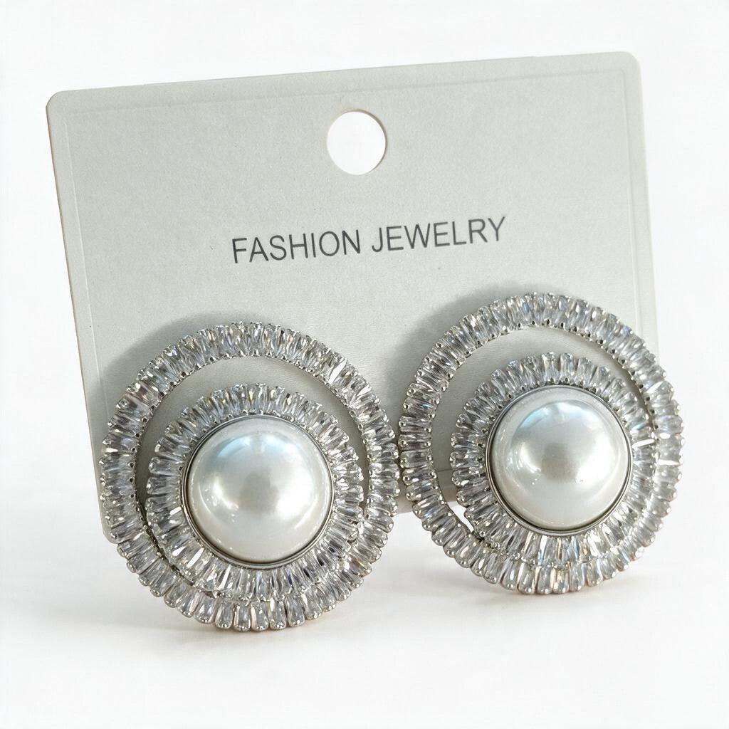 Pair of silver tone pearl spiral earrings with baguette crystals on a white display card