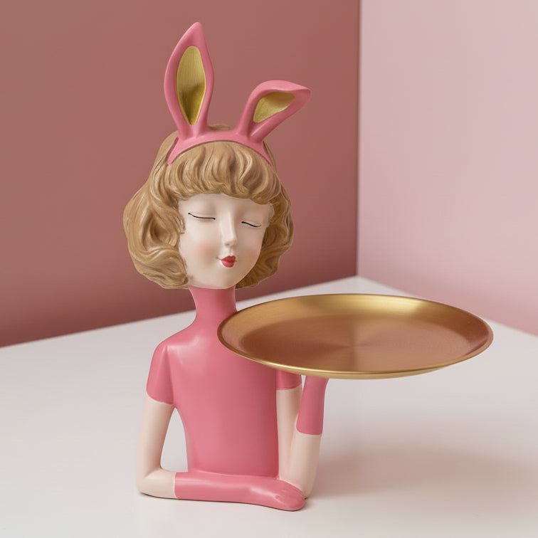Pink bunny ears lined in gold, blonde bob, gold tray balanced on one extended arm