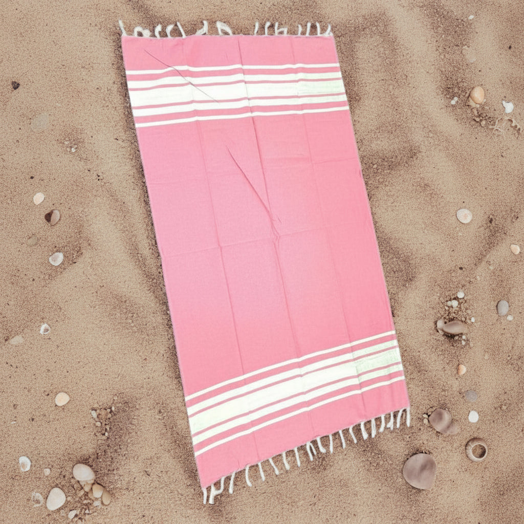 Pink and white striped towel on sand