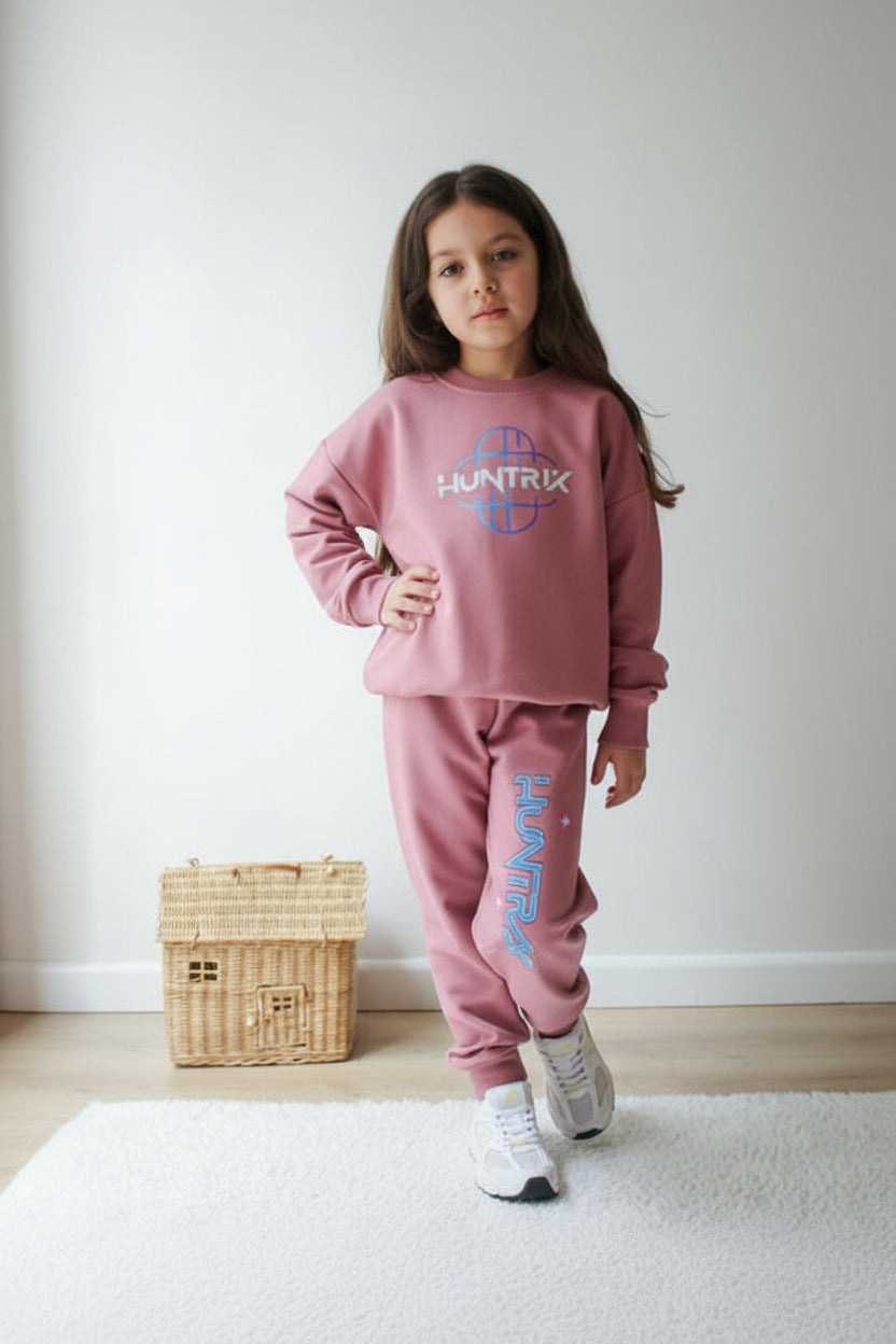 Front view of a mauve pink Huntrix globe logo sweatshirt with side print joggers for girls