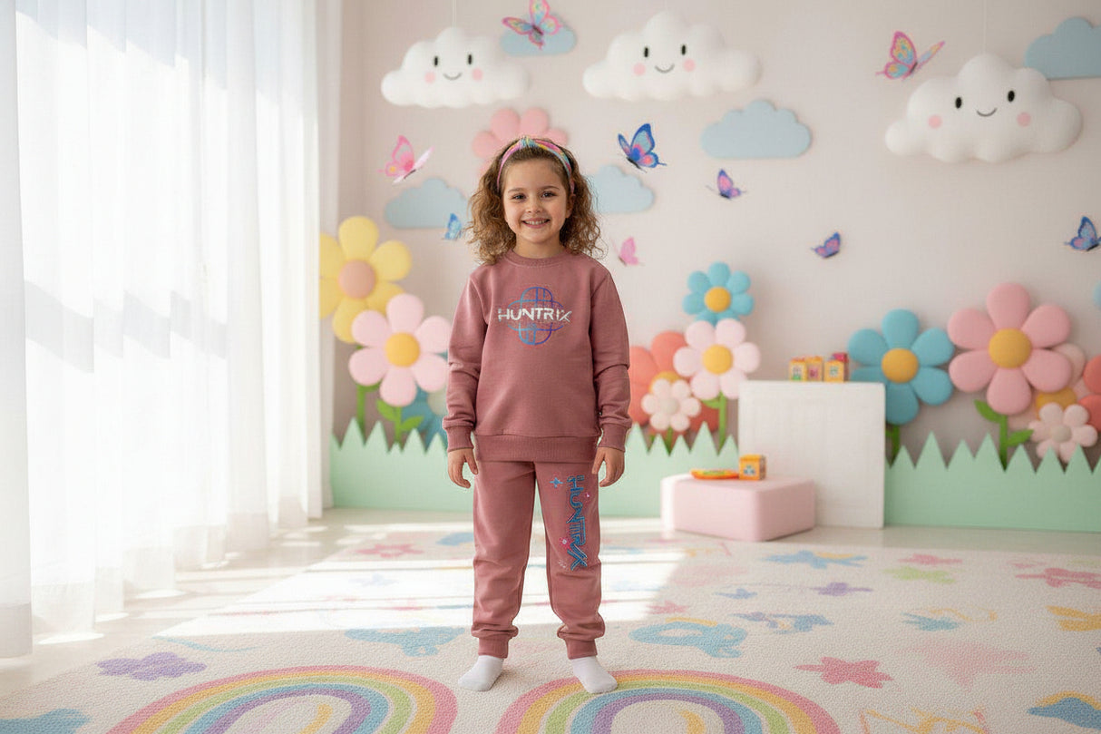 Dusty pink girls set with a Huntrix logo sweatshirt and matching printed joggers in a playroom