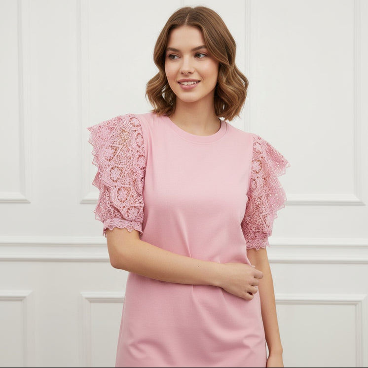 Woman wearing a pink top with lace sleeves against a white background