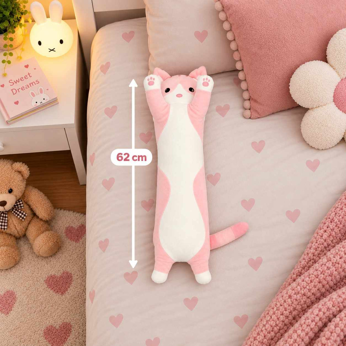 Pink long cat body pillow plush lying on a heart print bed next to a 62 cm measuring line