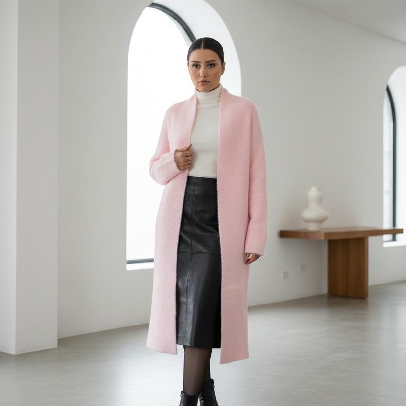 Woman wearing a pink long coat in a minimalistic room