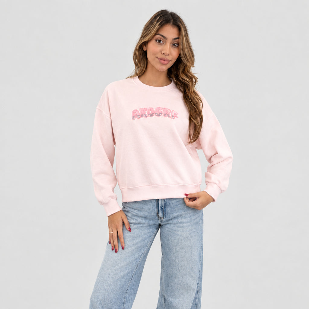 Pale pink sequin letter sweatshirt worn with wide light jeans against a plain grey wall