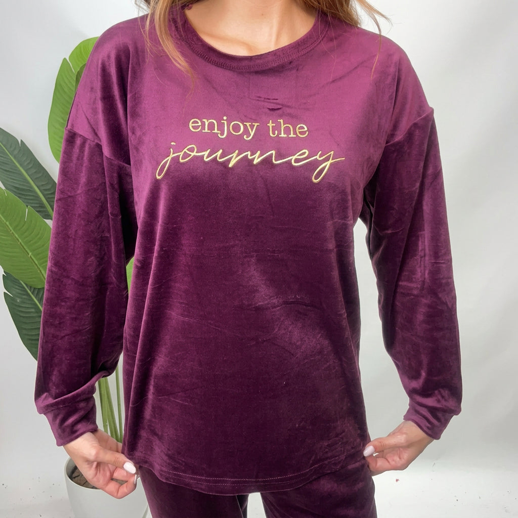 Close up of a plum velvet top with gold Enjoy The Journey lettering on the chest