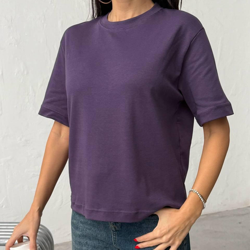 Person wearing a purple tshirt and blue jeans against a plain background