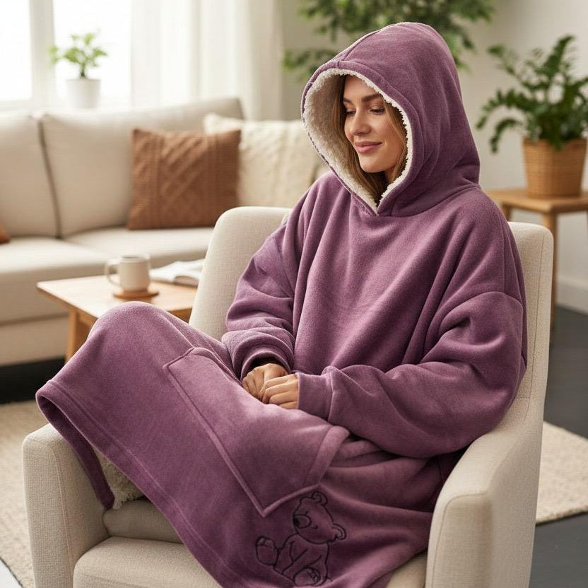 Curled in a boucle armchair, hood raised, in a dusty mauve blanket with an ivory sherpa lining
