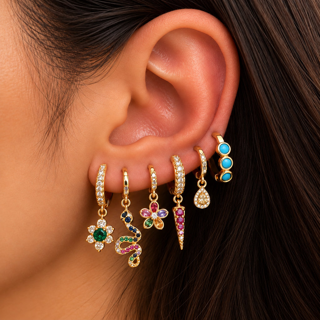 Ear stacked with gold huggies with an emerald flower, rainbow snake, petal flower, red spike and turquoise hoop