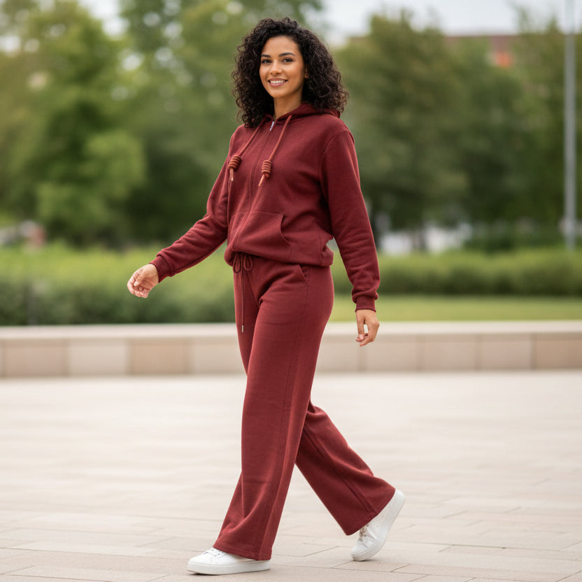 Woman in a red casual outfit walking outdoors with greenery in the background