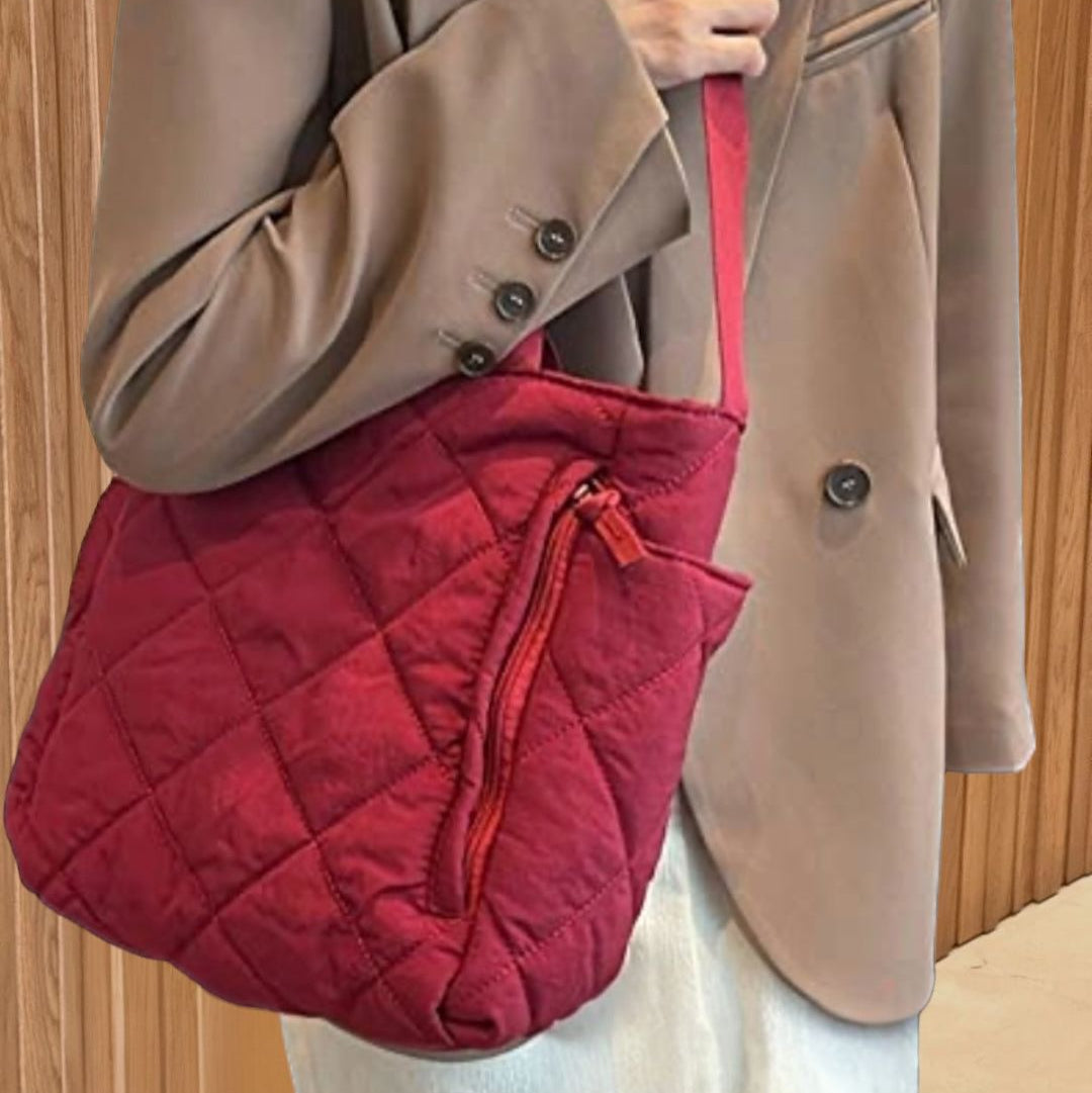 Red quilted handbag held by a person wearing a brown coat