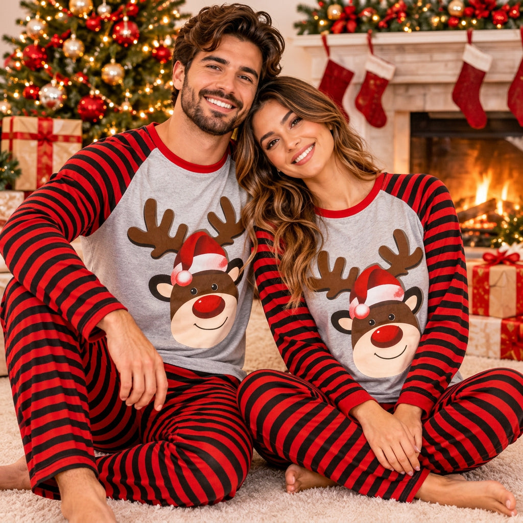 Smiling couple in matching reindeer Christmas pyjamas with red and black striped sleeves and pants by a fireplace