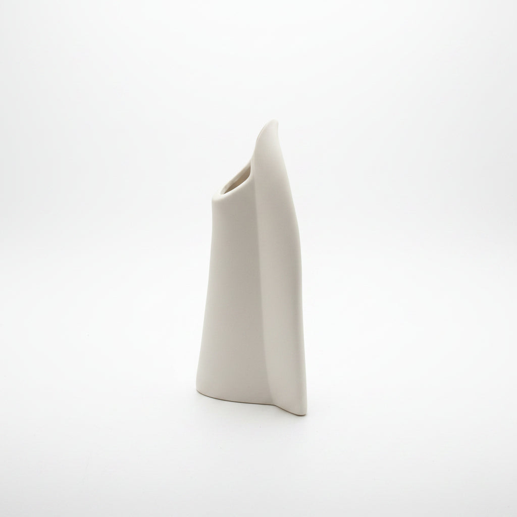 Edge on studio view of the disc vase, a narrow curved slab with an angled oval mouth