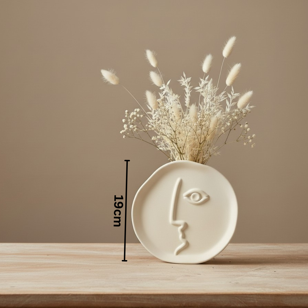 Ceramic vase with dried flowers on a wooden surface against a beige wall
