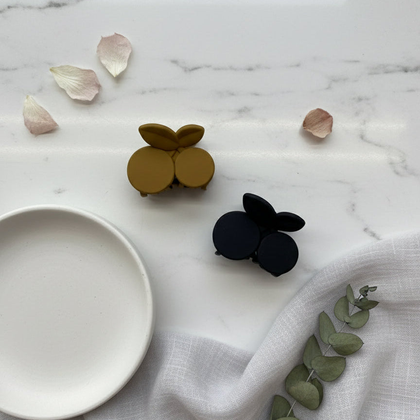 Mustard and navy round petal claw clips on white marble with rose petals
