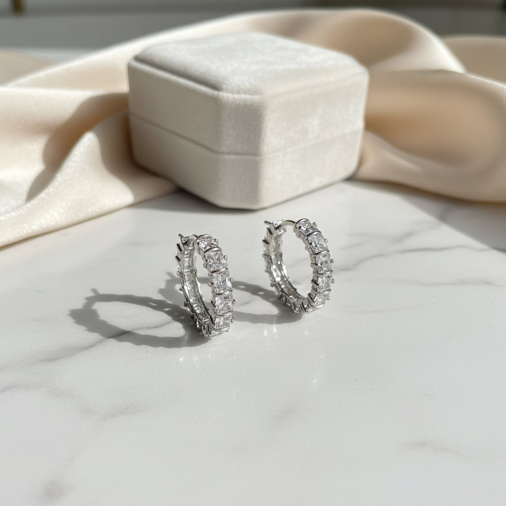 Silver crystal hoop earrings on a marble surface
