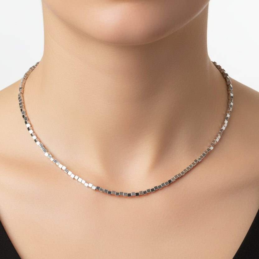 Silver cube necklace worn by a woman on a white background