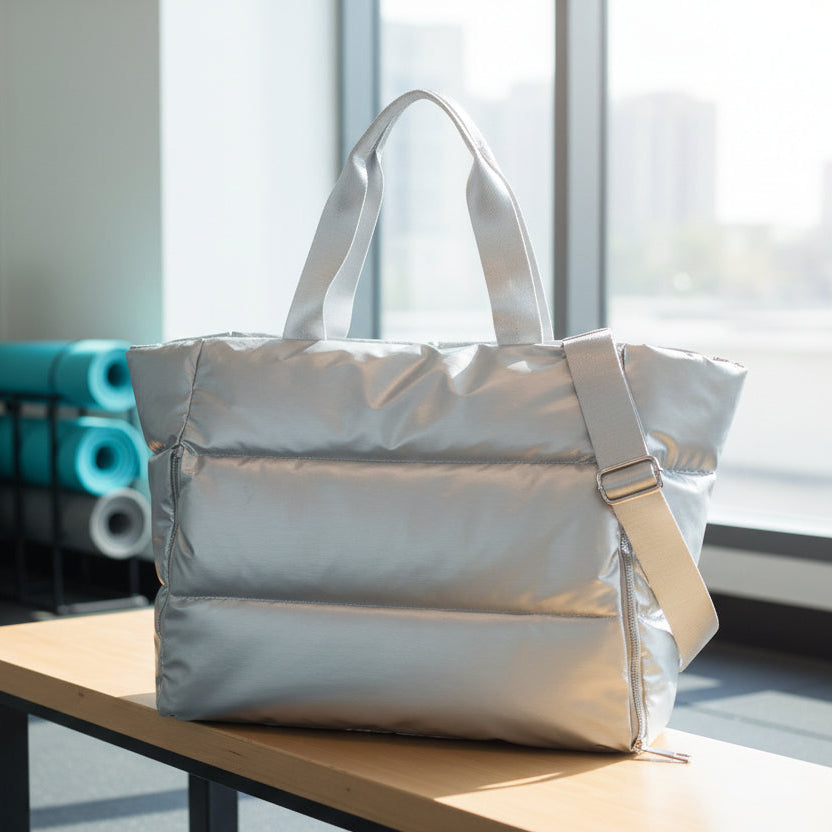 Silver puffer tote bag on a wooden bench showing the quilted padded texture