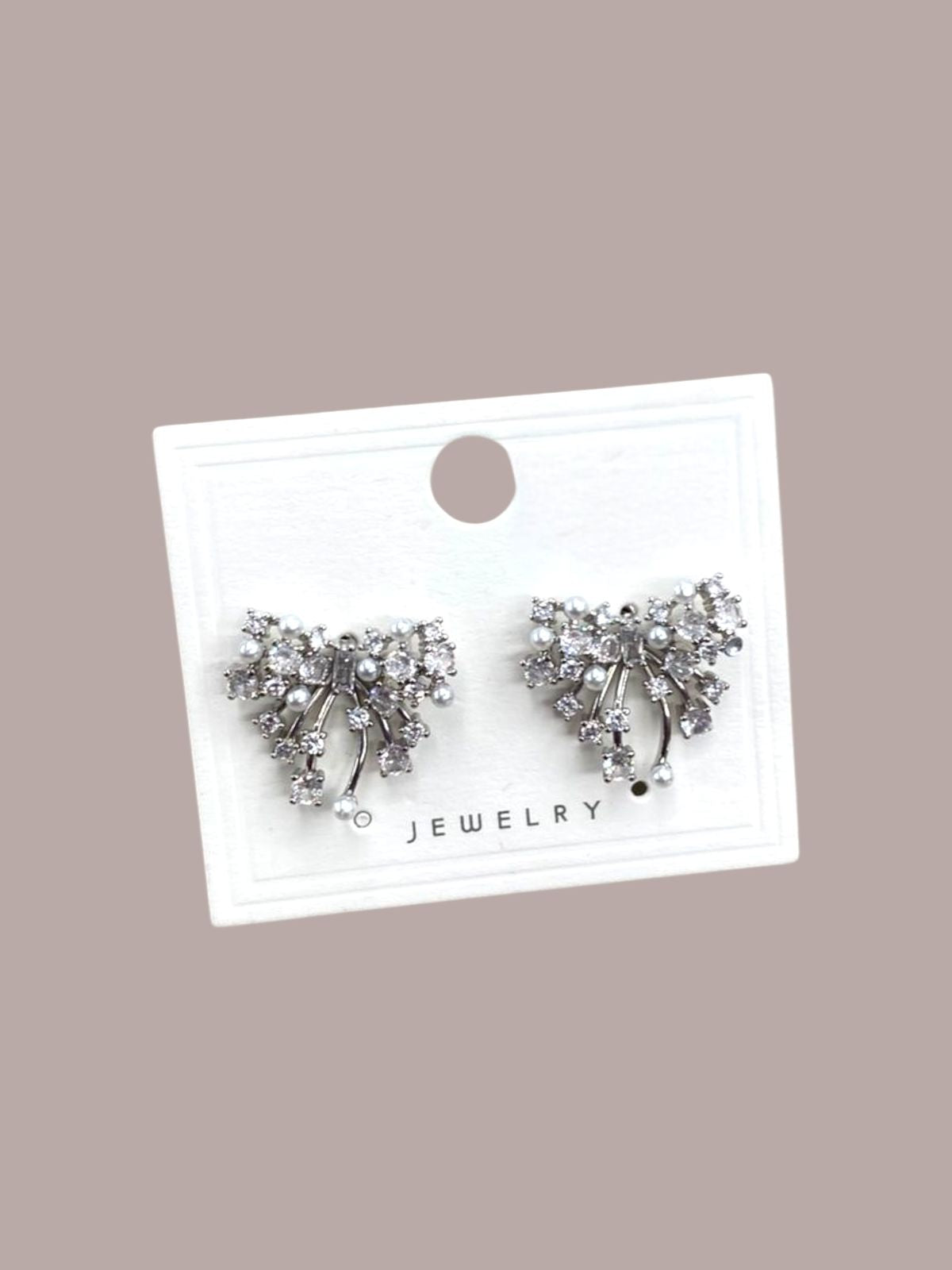 Pair of silver bow-shaped earrings on a white card with 'Jewelry' text against a beige background
