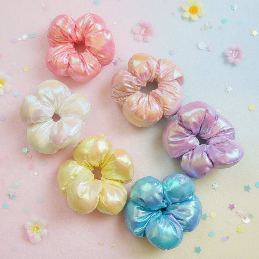 Set of six puffy metallic scrunchies in pink, ivory, peach, lilac, yellow and aqua on a pastel confetti backdrop